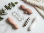 Collection of body-safe sex toys made from medical-grade silicone, glass, and stainless steel displayed on marble surface